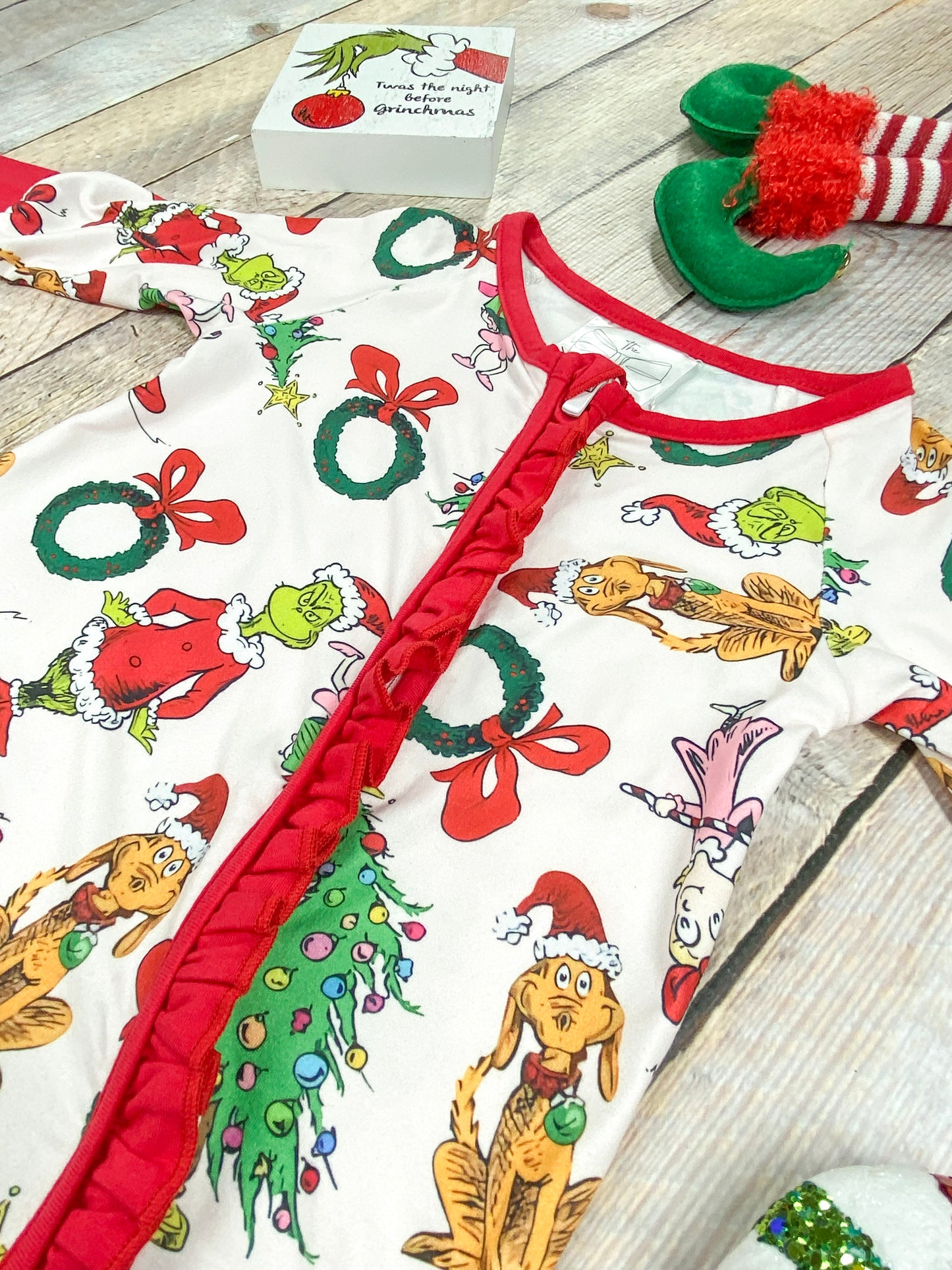 Close-up view of red ruffle trim along the front zipper of the infant Grinchmas romper, adding a festive and feminine touch to the playful Christmas outfit.