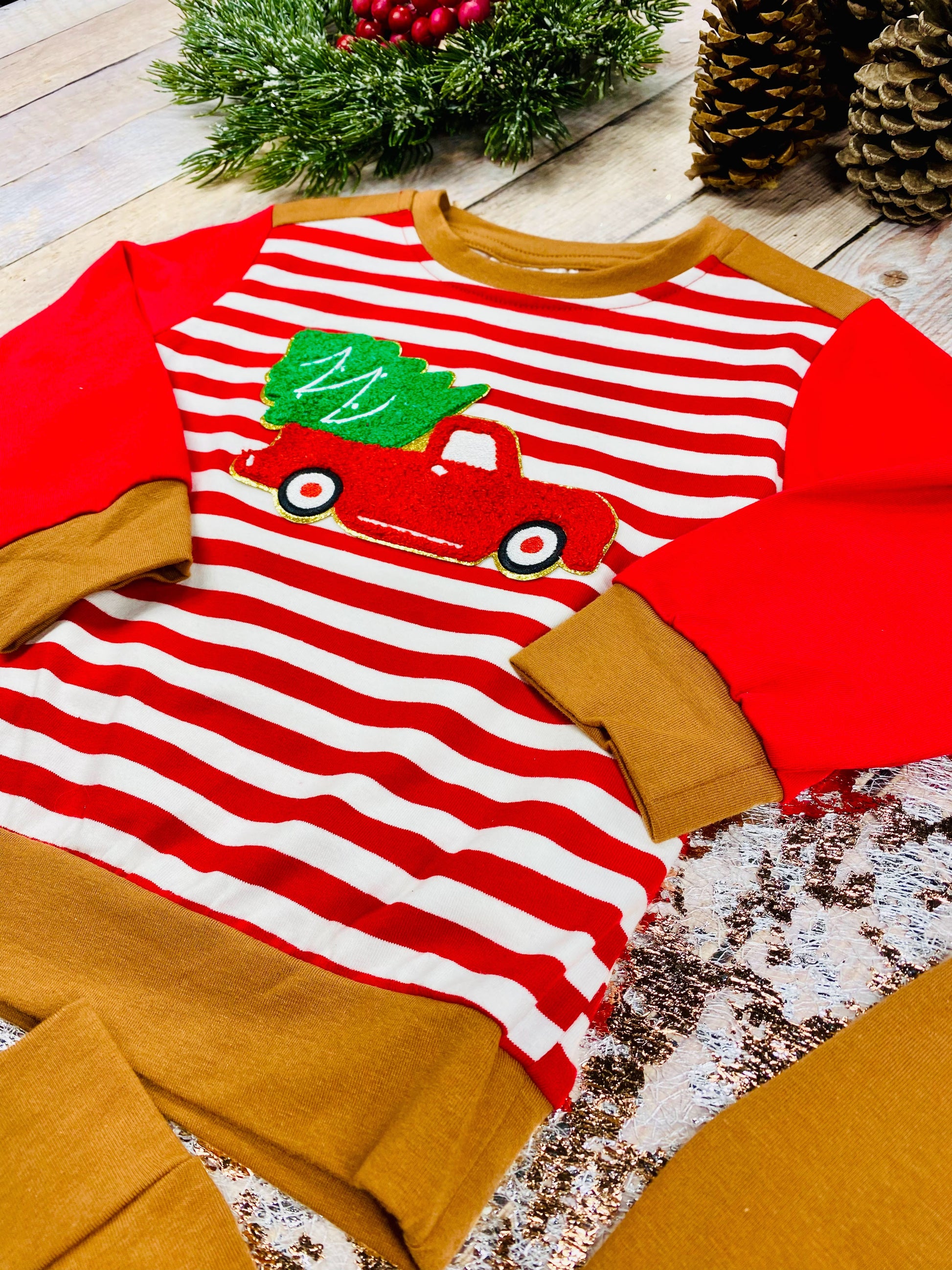 Close-up of boys’ holiday shirt with red truck carrying Christmas tree applique and red-and-white striped sleeves.
