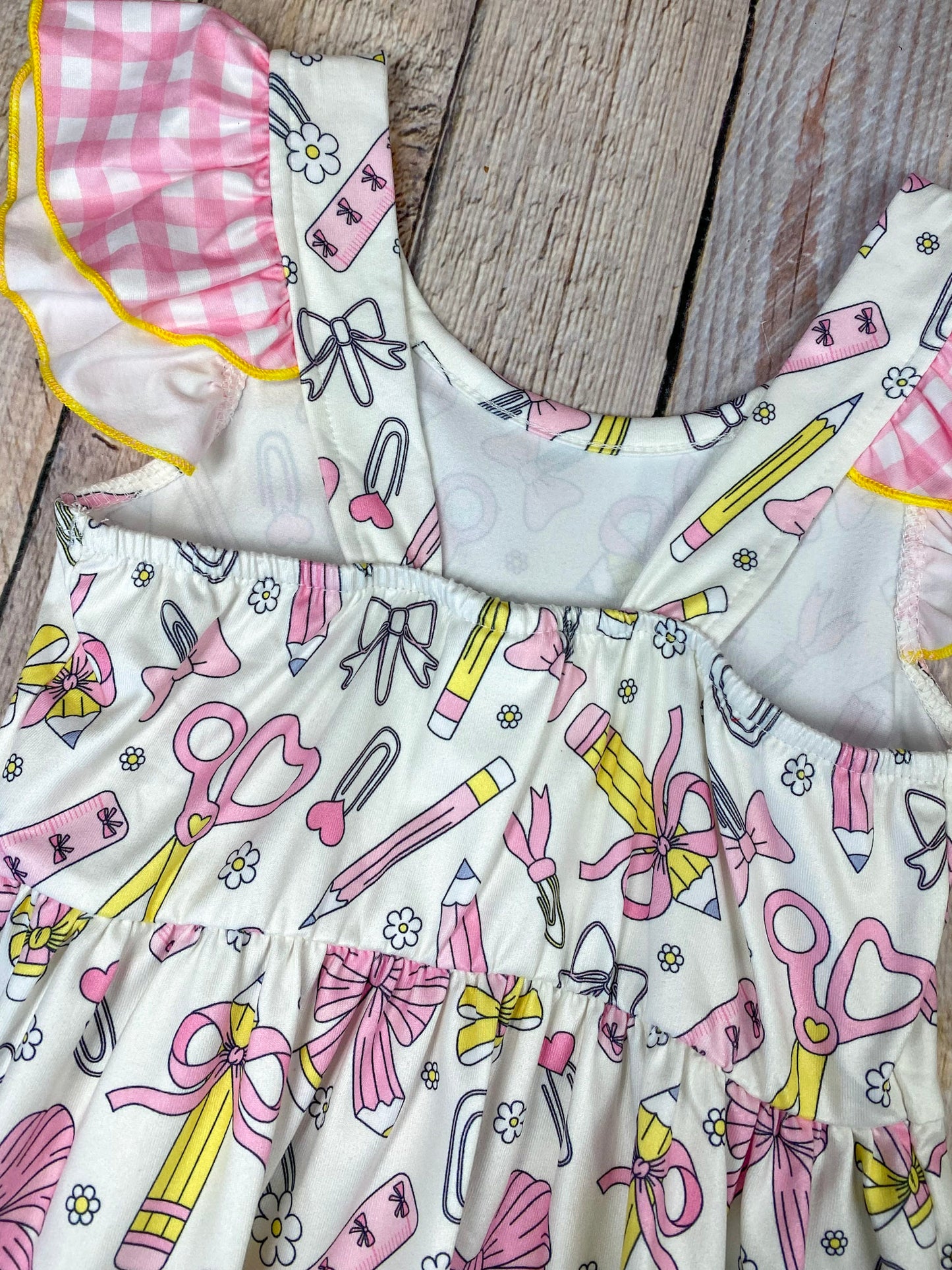 Children's dress with stationery-themed print on a wooden background