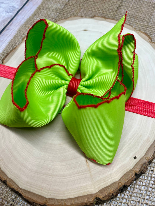 Green hair bows with red edges on a wooden surface - Alternative view