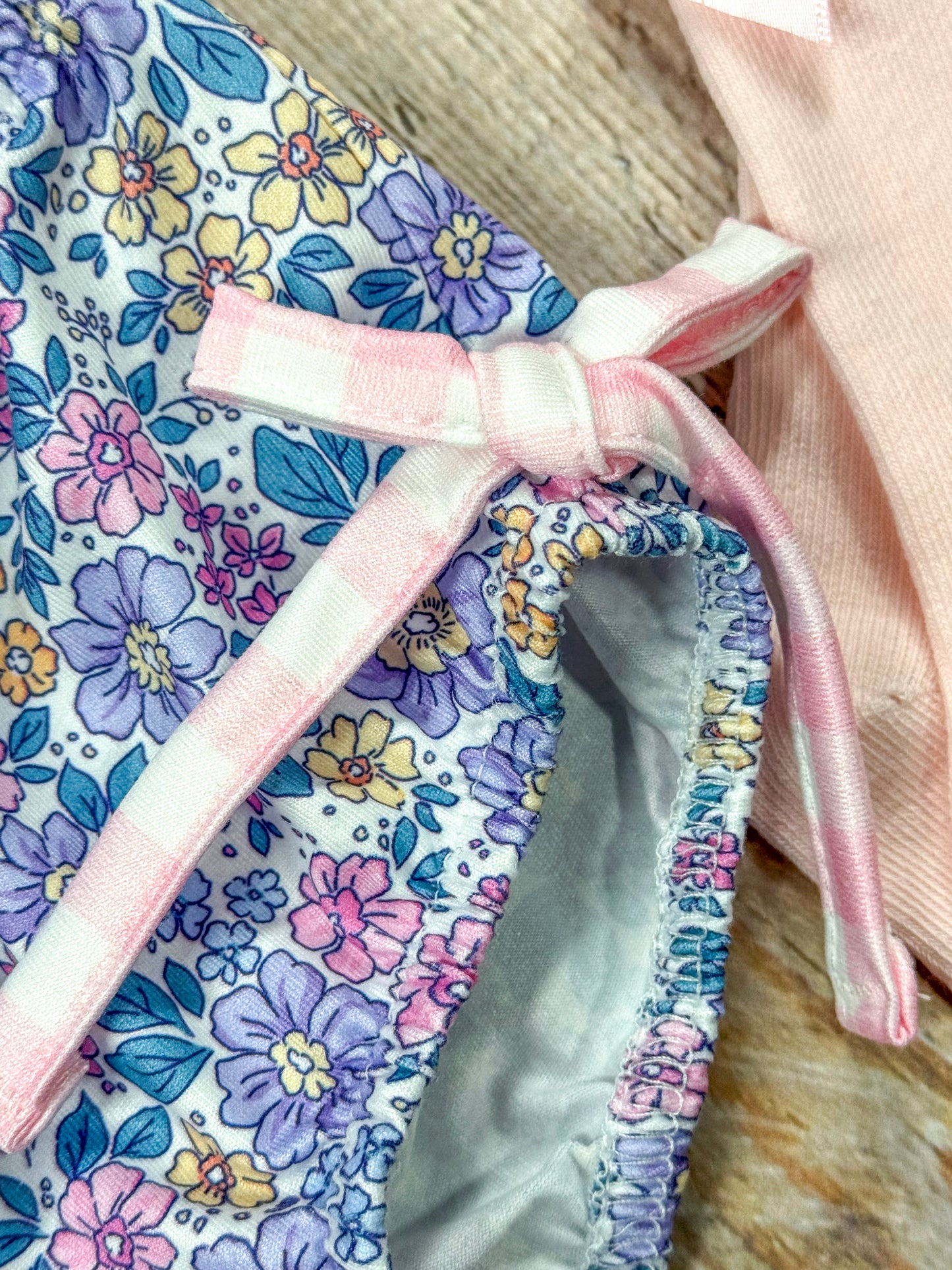close up of gingham bow tie on side of floral bottoms of romper