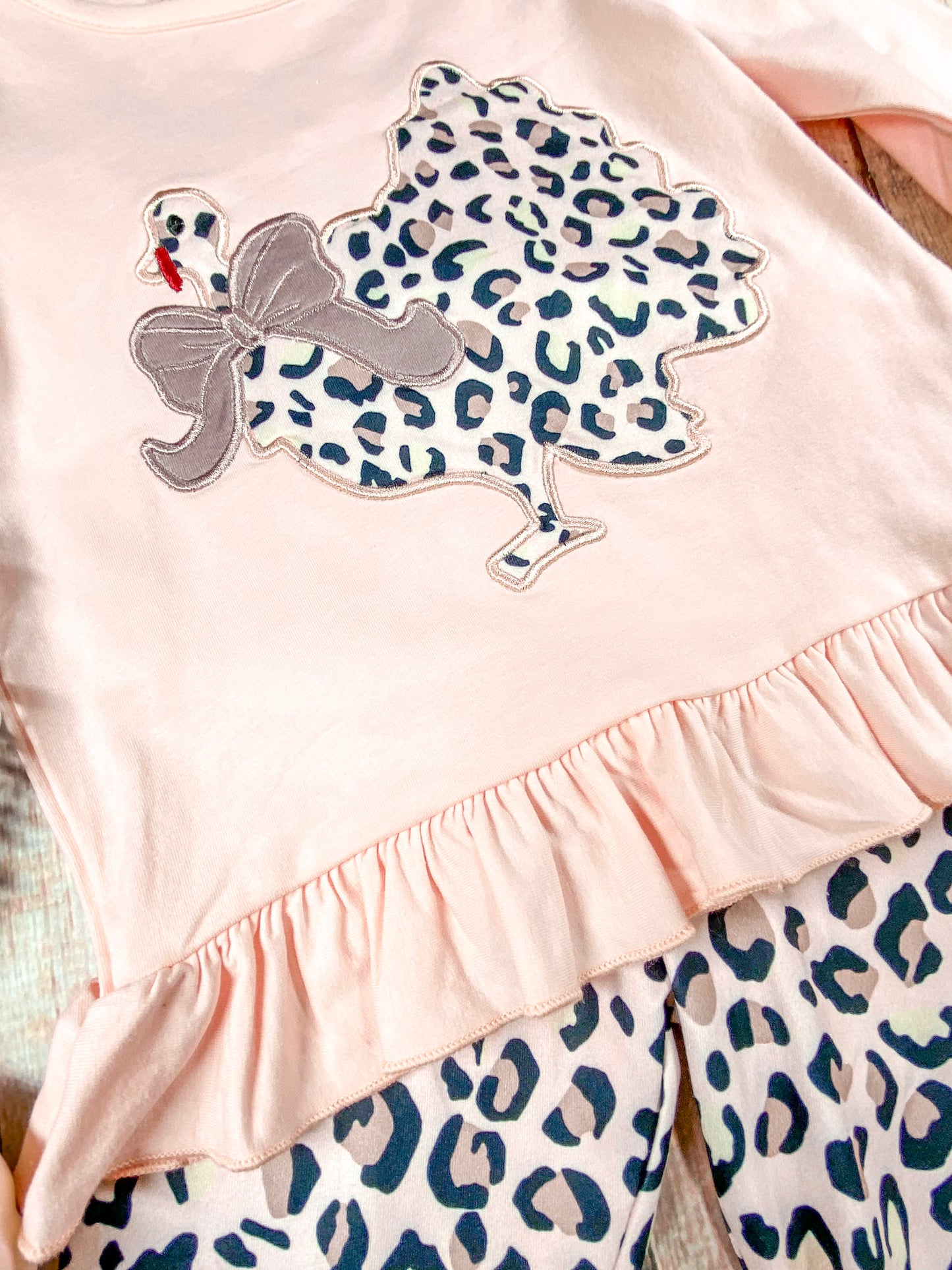 close up of the animal print chicken with a bow around its neck and the bottom of shirt