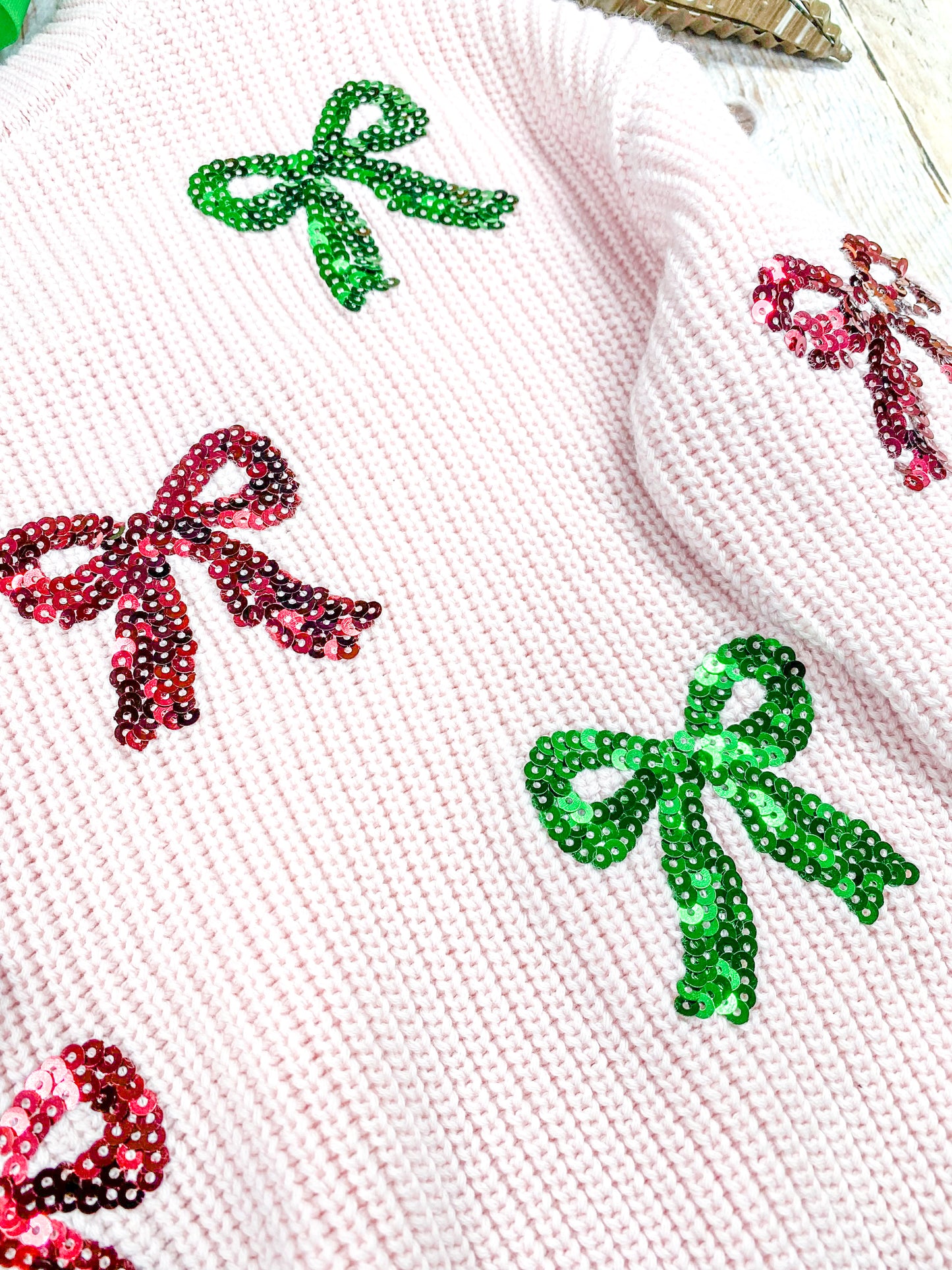 close up of the red and green sequin coquette bows on front of sweater