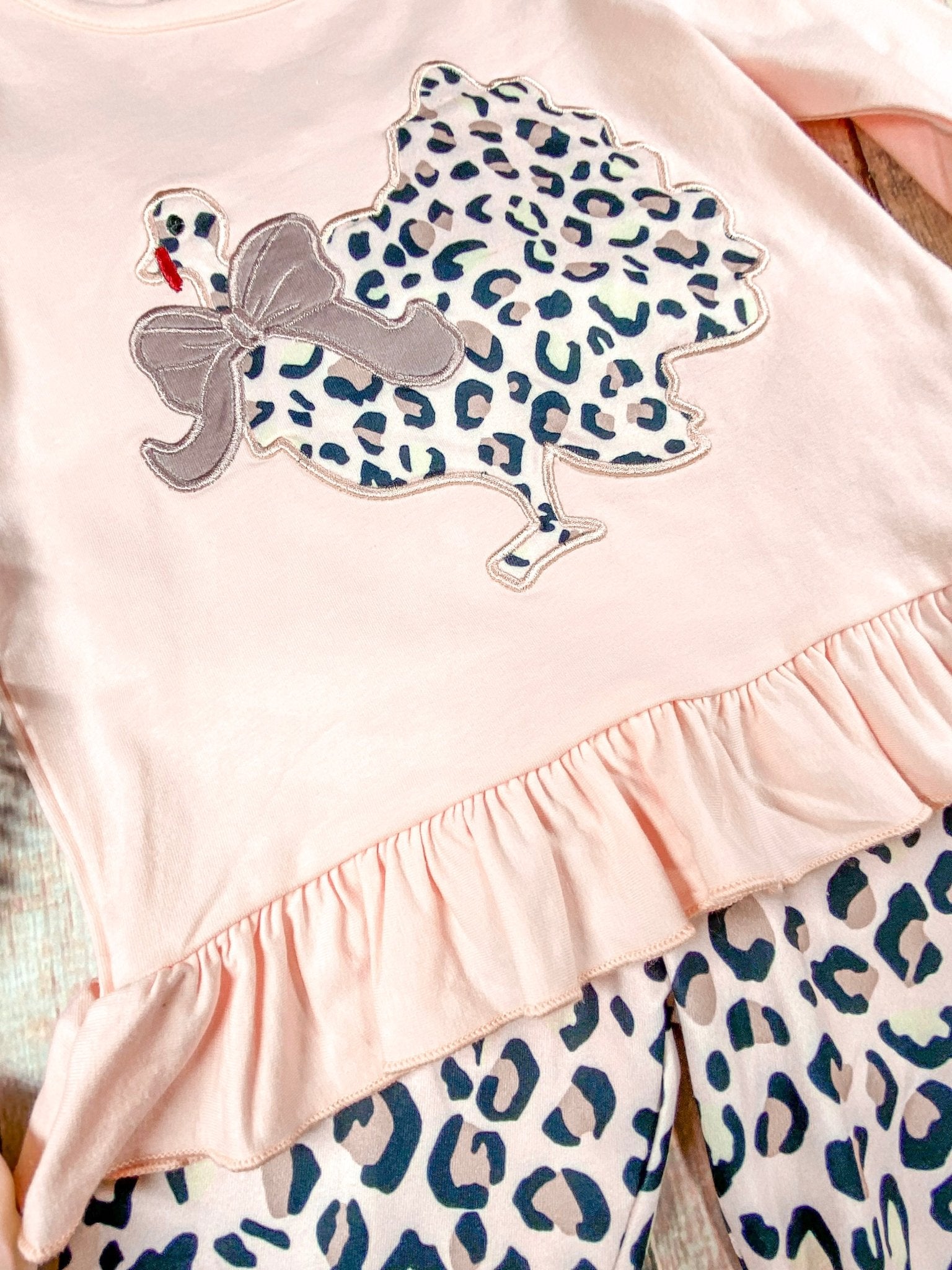 close up of the animal print chicken with a bow around its neck and the bottom of shirt