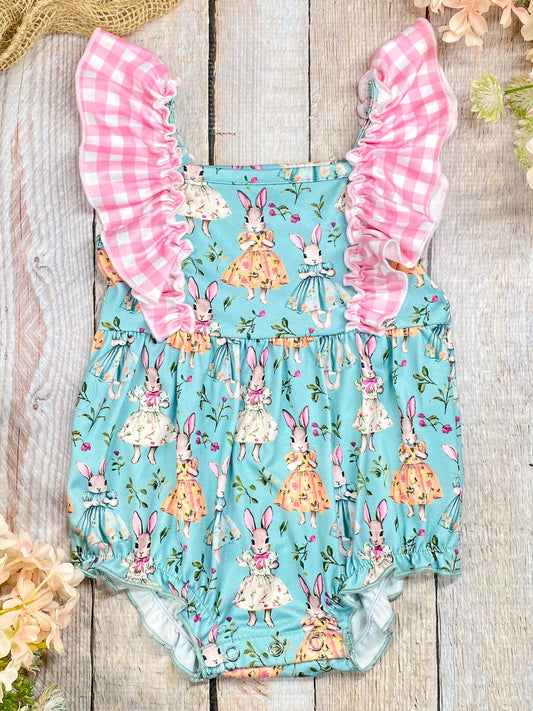 Children's romper with bunny print and pink ruffled sleeves on a wooden surface. - Alternative view