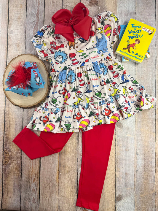 Children's outfit with Dr. Seuss-themed top, red pants, and matching headband on a wooden surface. - Alternative view