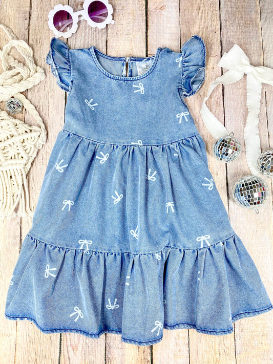 Blue denim bow print dress with ruffled sleeves and bottom on a wooden surface - Alternative view