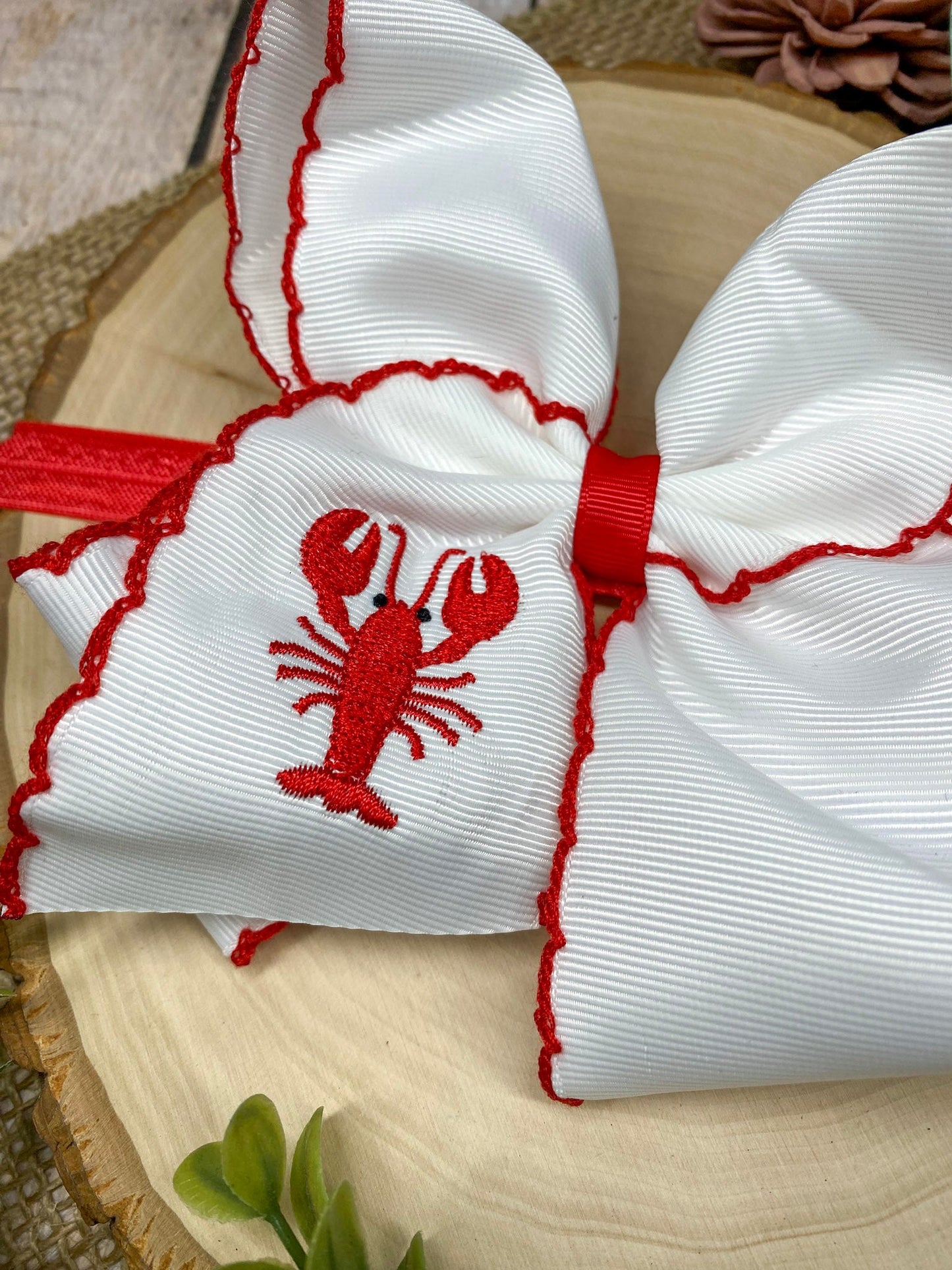 The Crawfish & Lobster Embroidered Moonstitch Headband on a wooden background