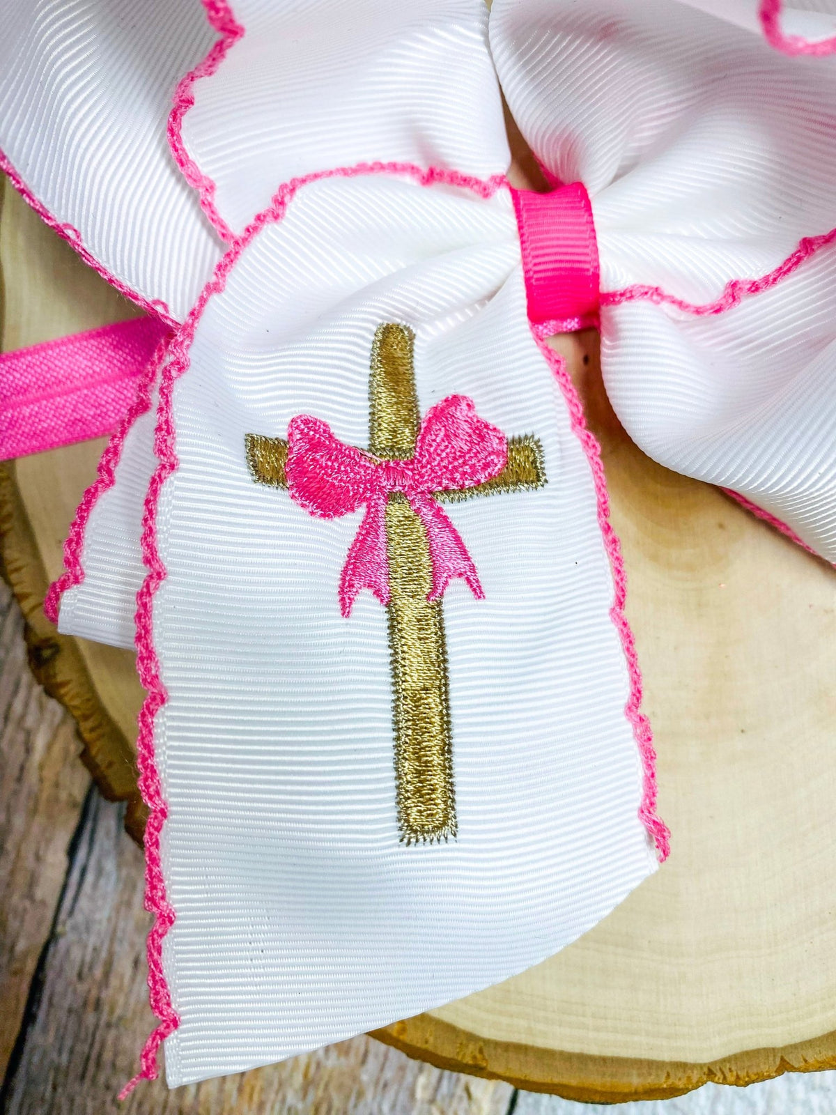 Close-up of gold cross embroidery on moonstitch bow headband