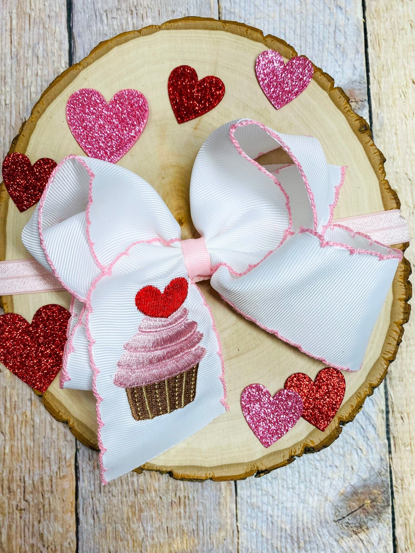Hair bow with cupcake and heart designs on a wooden background