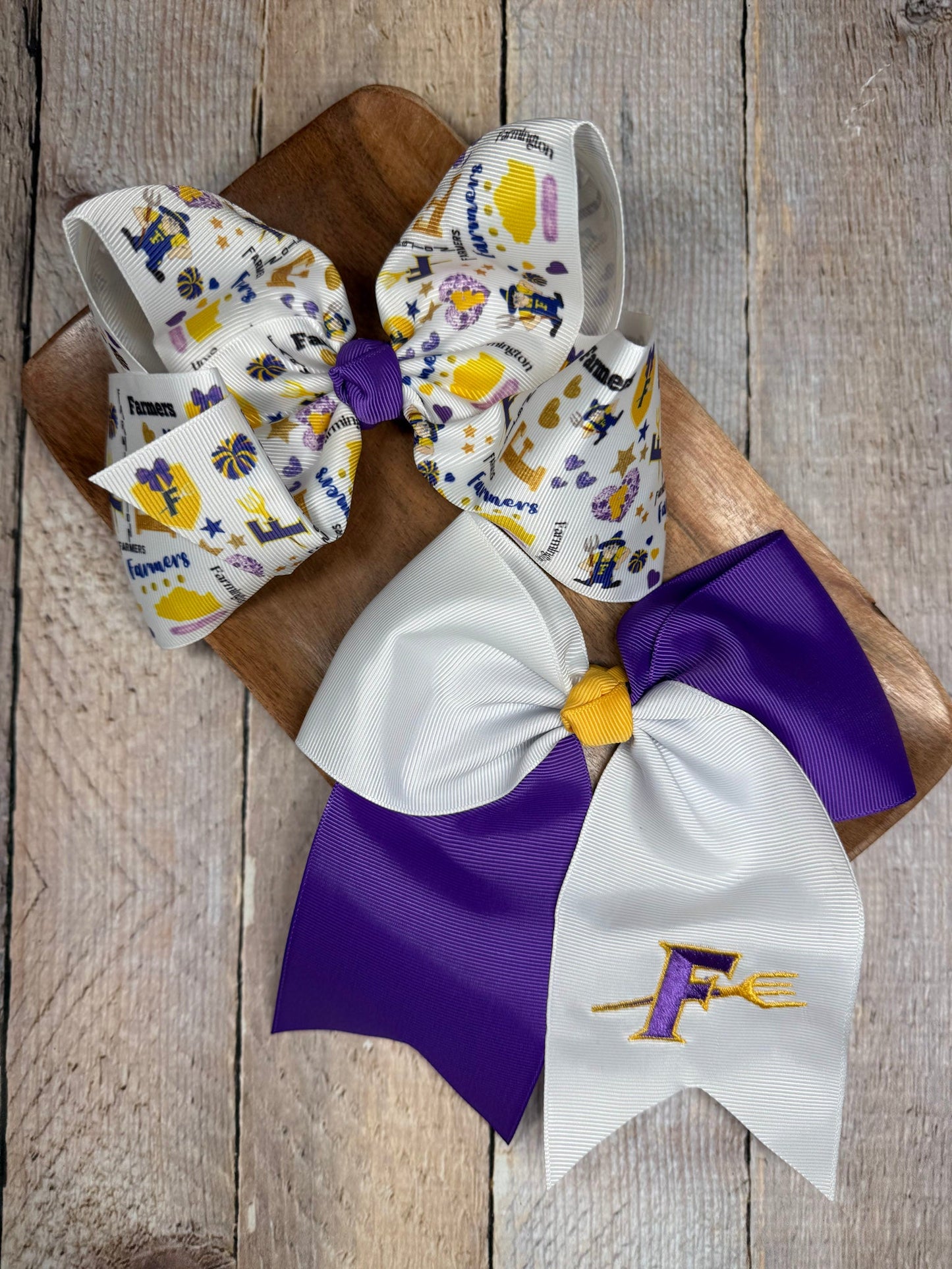 Two decorative bows with purple and white design on a wooden surface