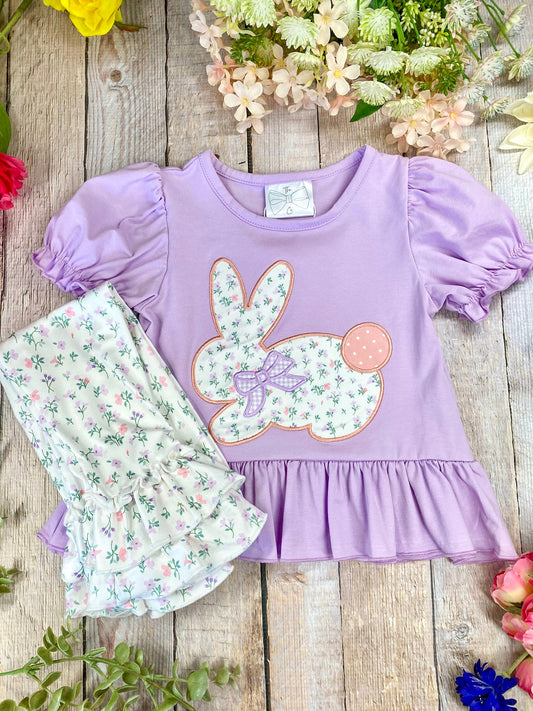 Easter outfit with purple top and floral pants on a wooden background - Alternative view