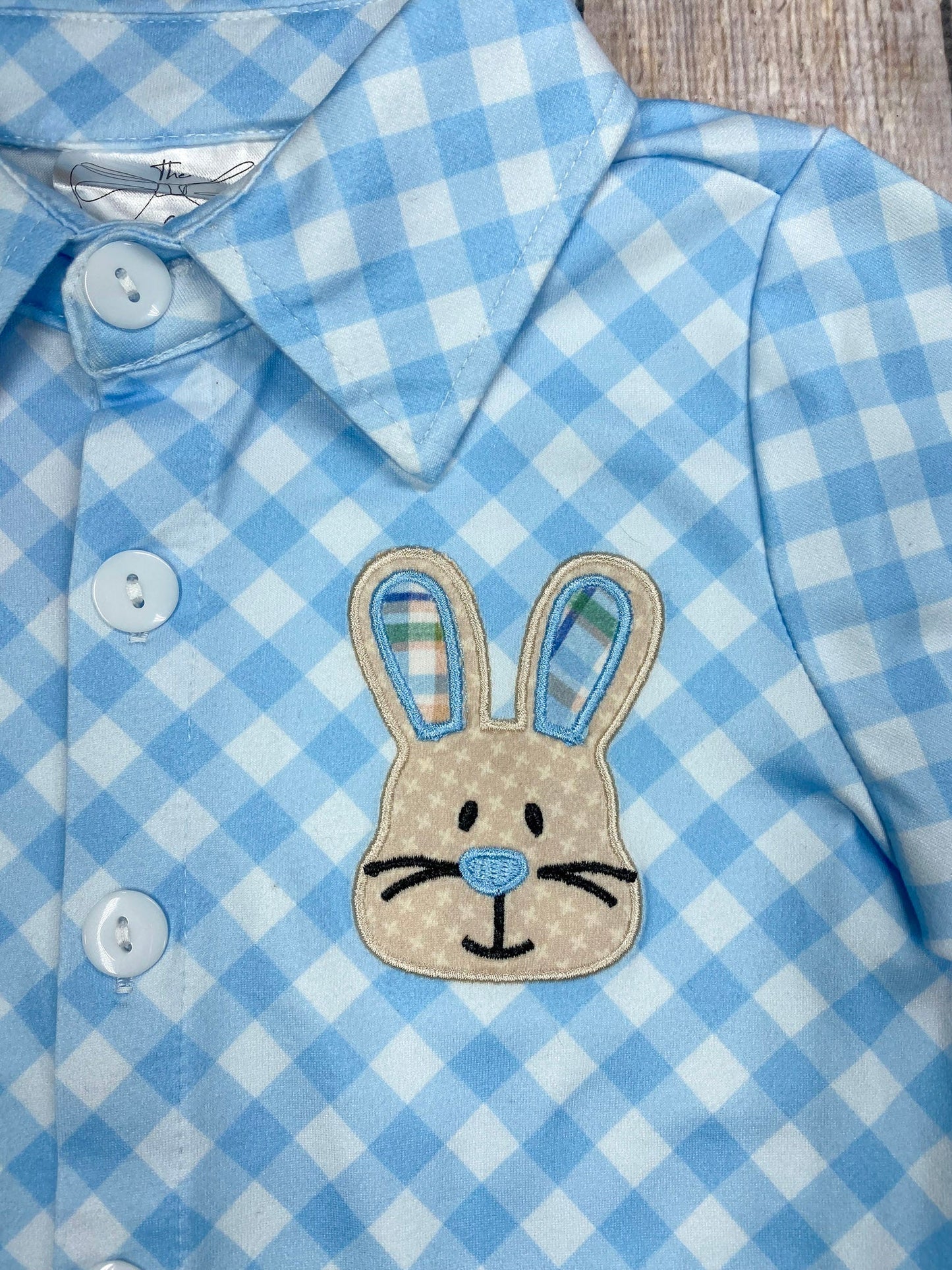 Blue checkered shirt with a bunny patch on a textured surface