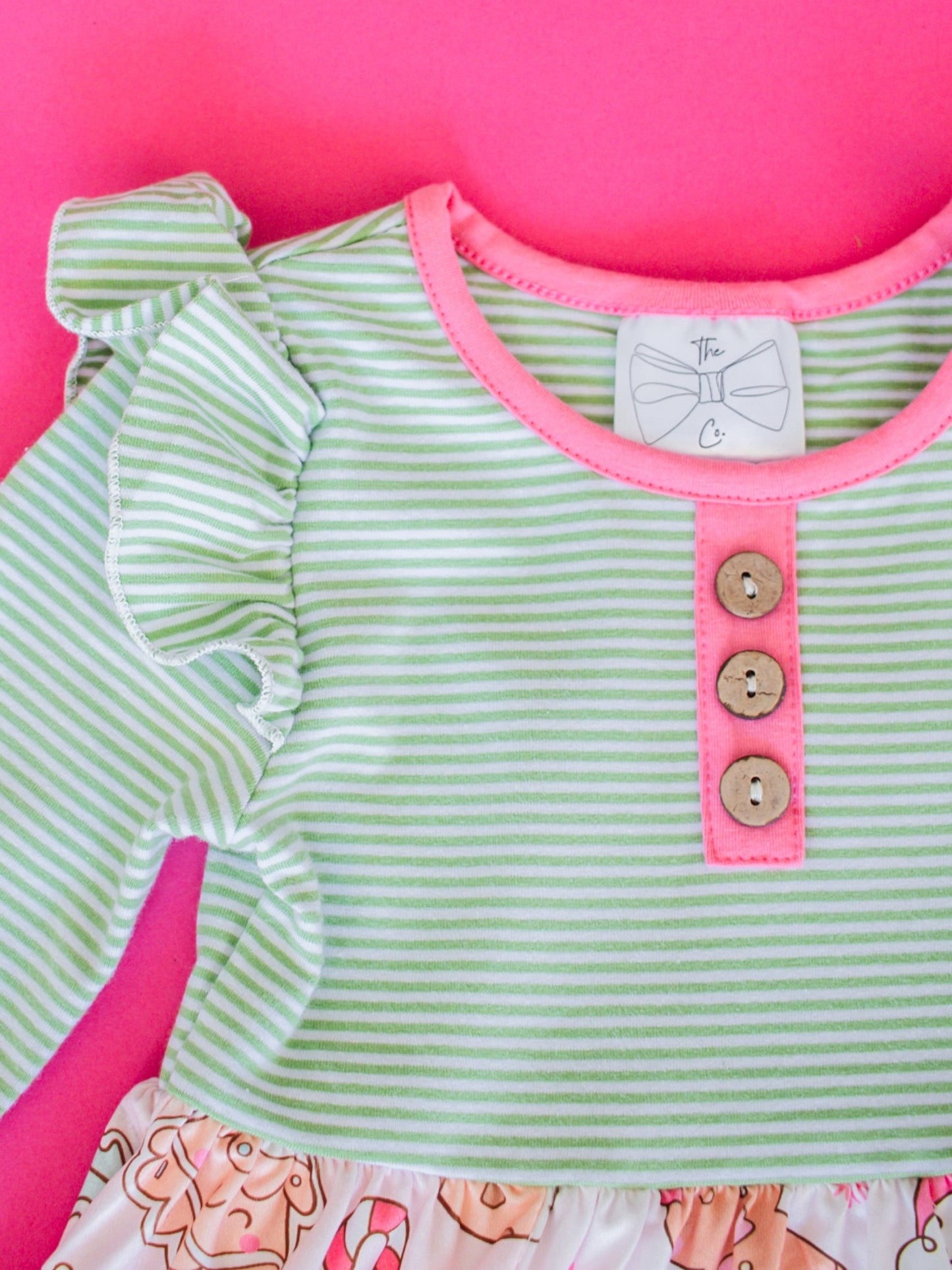Green and pink striped dress with buttons on a pink background