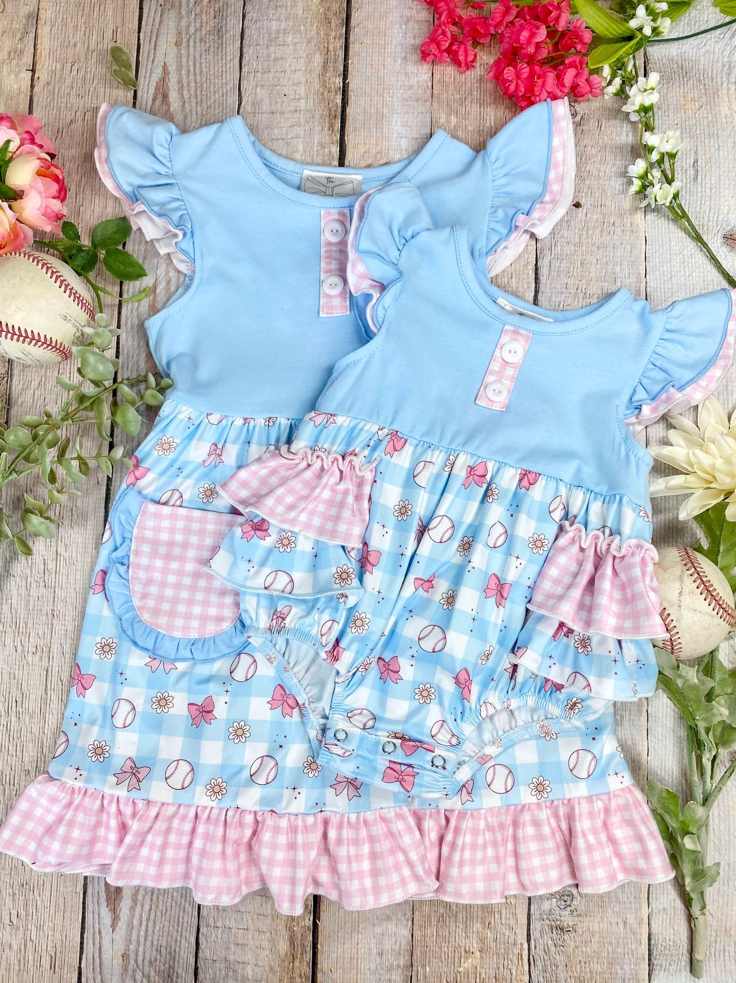 Baby romper and matching sibling dress with blue top and pink ruffles on a wooden background