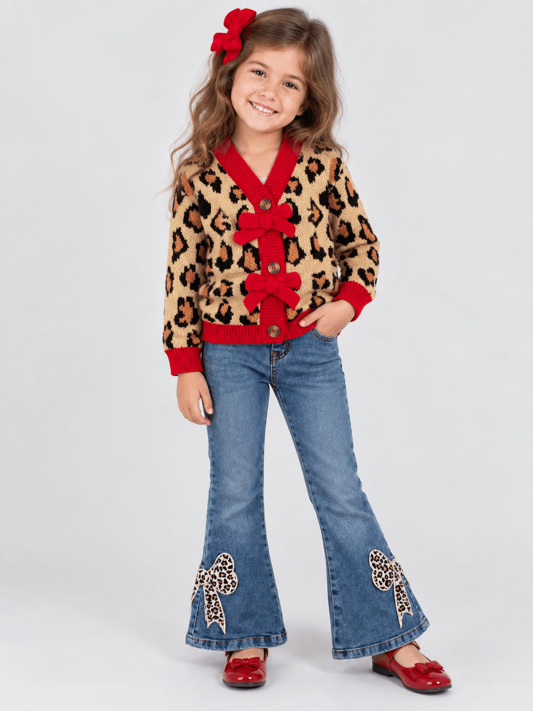 Girl wearing a leopard and red Christmas cardigan with leopard bow jeans