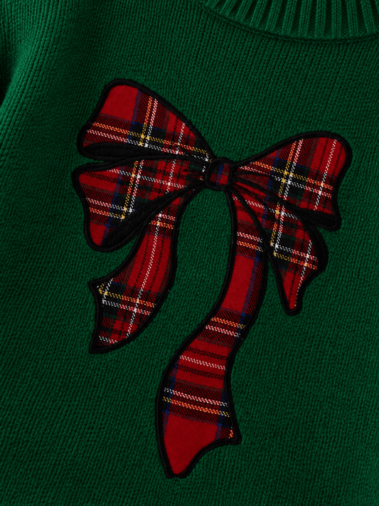 A close-up of green knit sweater featuring a large red tartan plaid bow - Alternative view