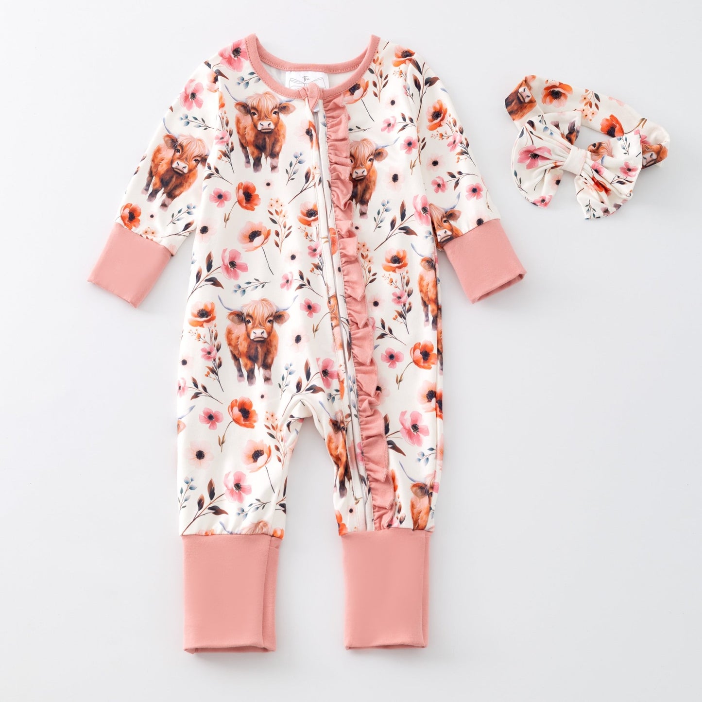 Baby onesie with cow and flower pattern on a white background