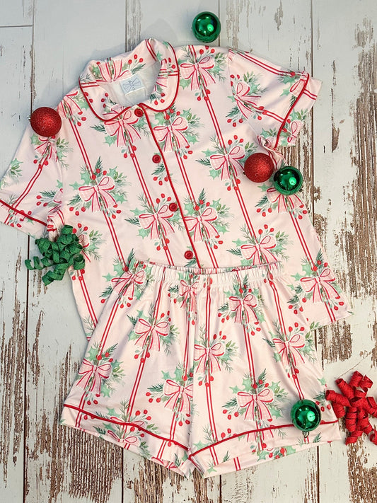 Children's Christmas-themed dress with red bows and berries on a wooden surface.