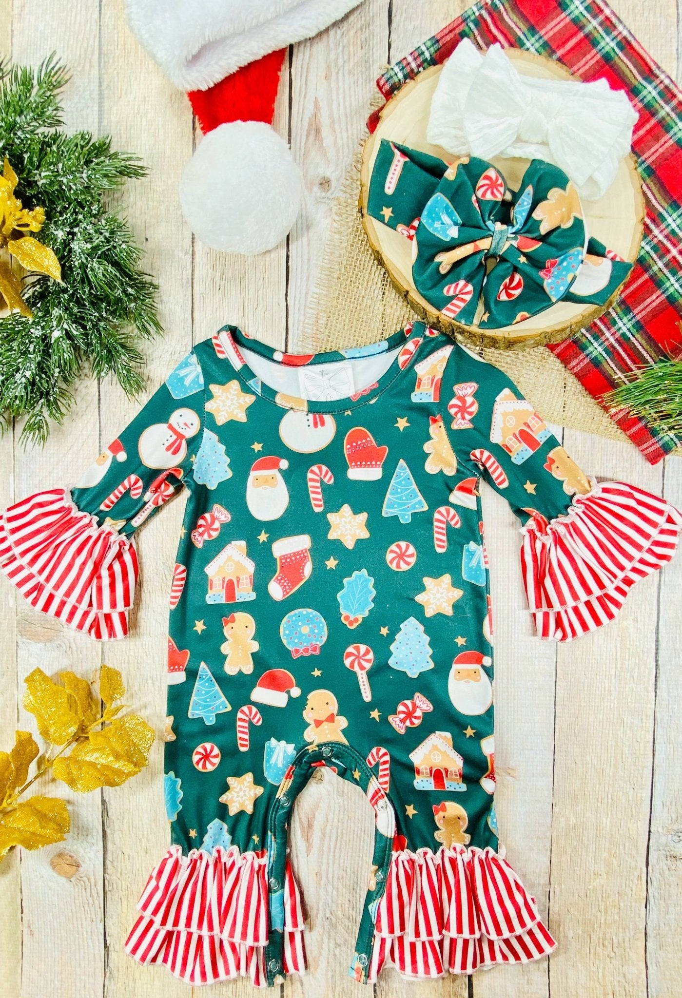 Infant girls’ Christmas romper with festive cookie print, red-and-white striped ruffle cuffs and ankles, matching fabric bow headband included.