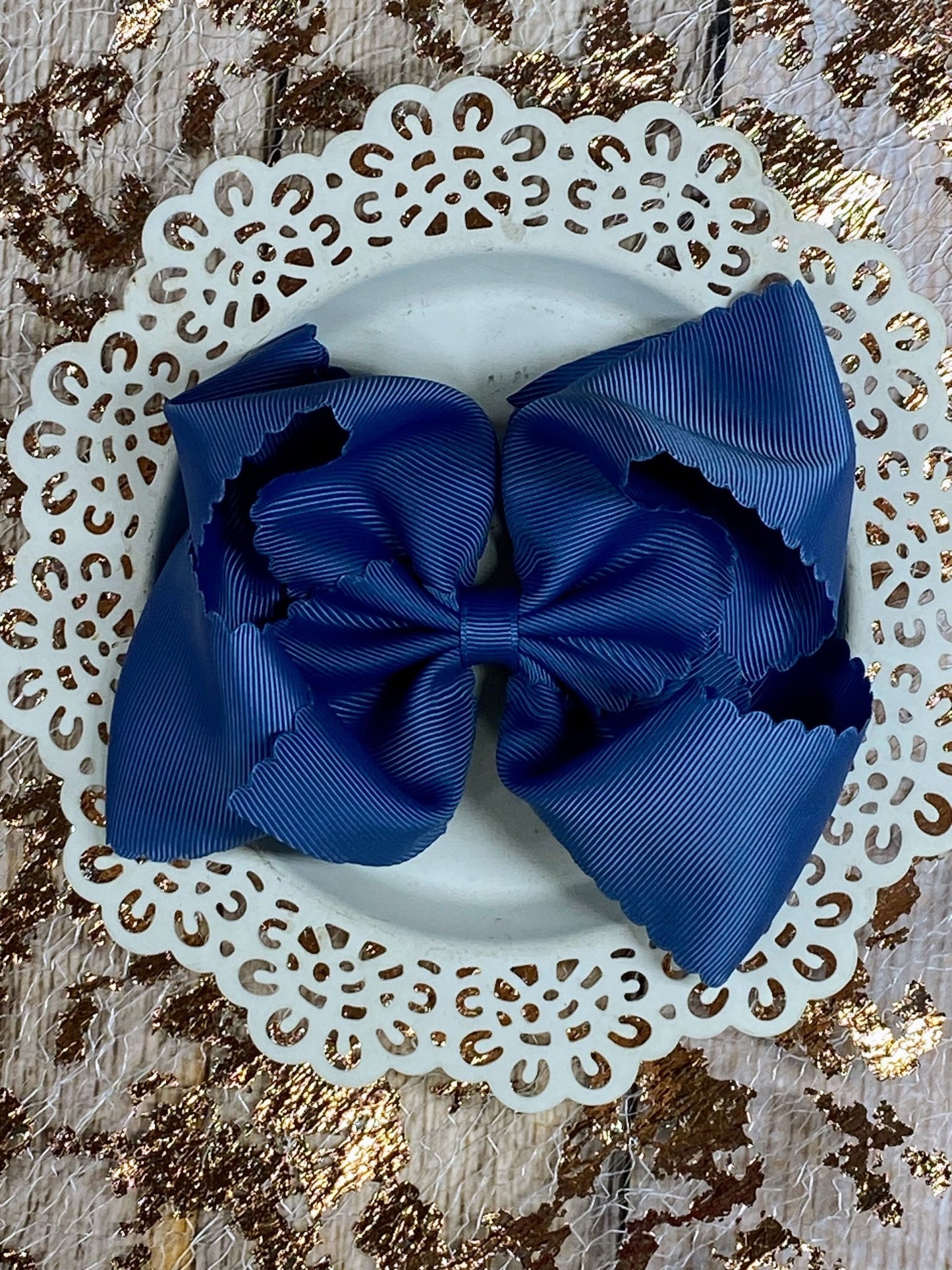 Blue hair bows on a white headband with a decorative lace background