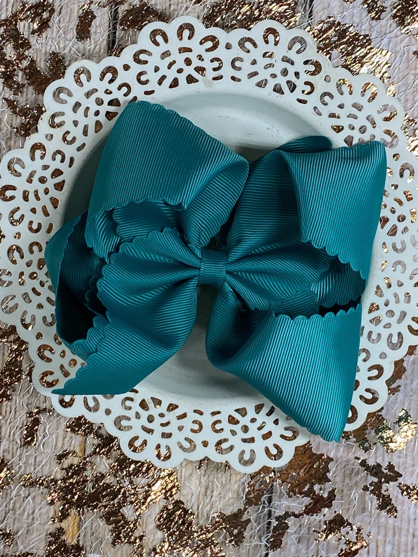 Teal bow on a white doily with gold leaf background