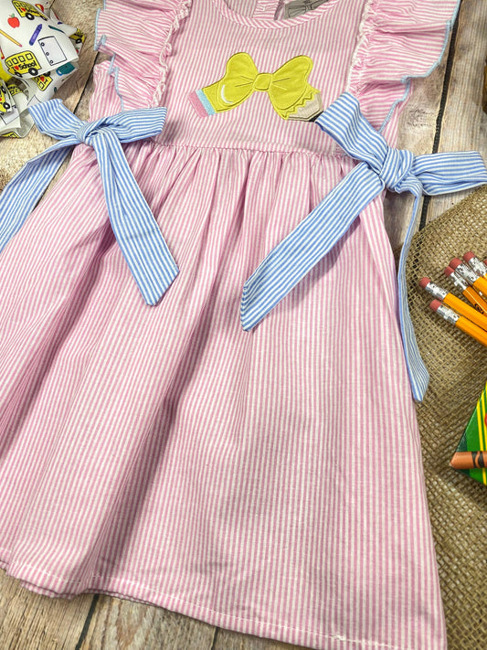 Pink striped dress with a bow on a wooden background - Alternative view