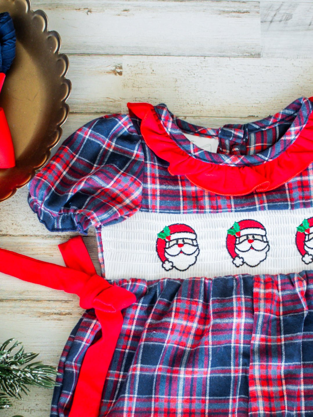 Plaid dress with red collar and Santa Claus embroidery on a wooden surface