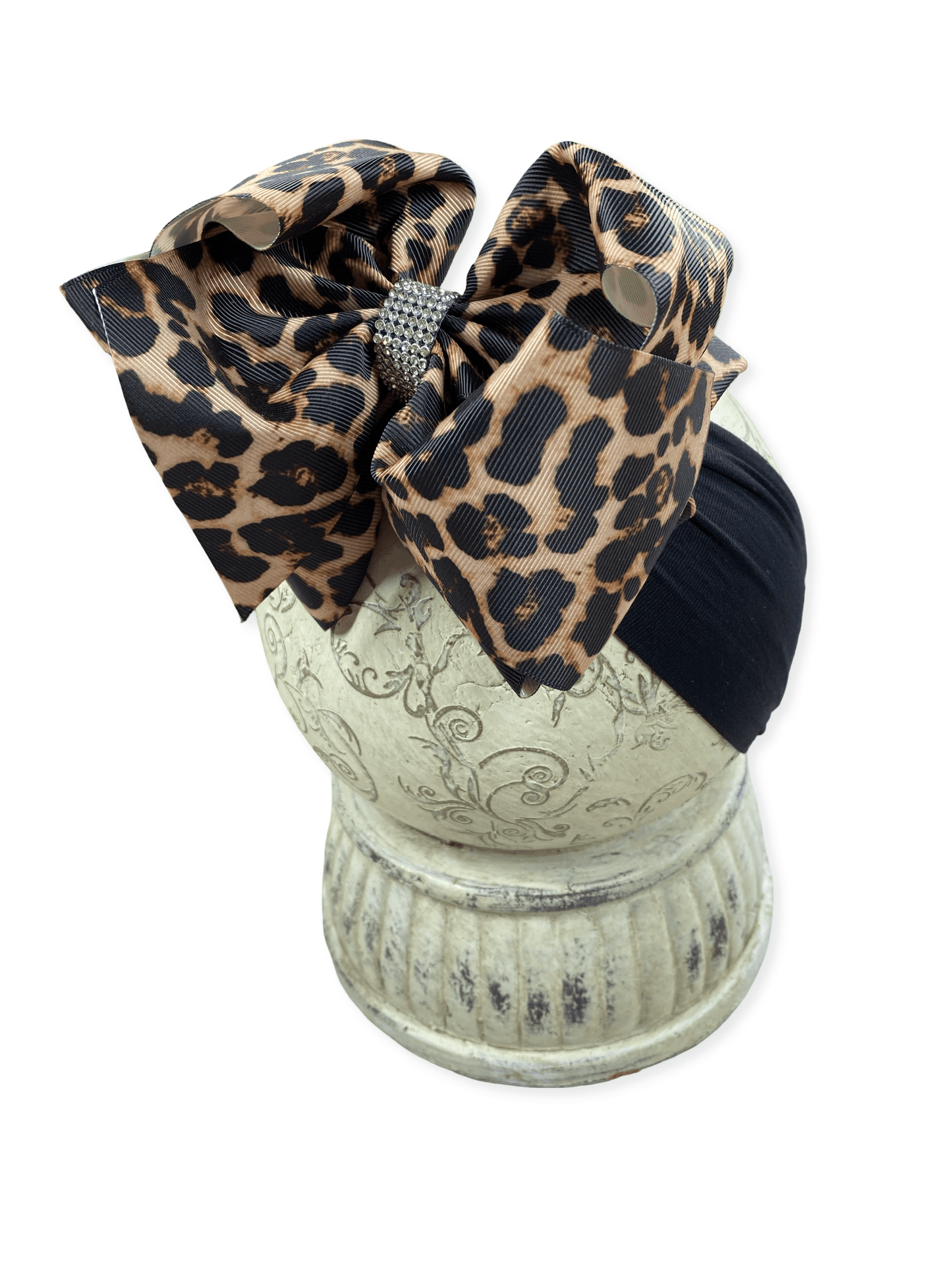 Leopard print hair bow on a decorative stand with a white background