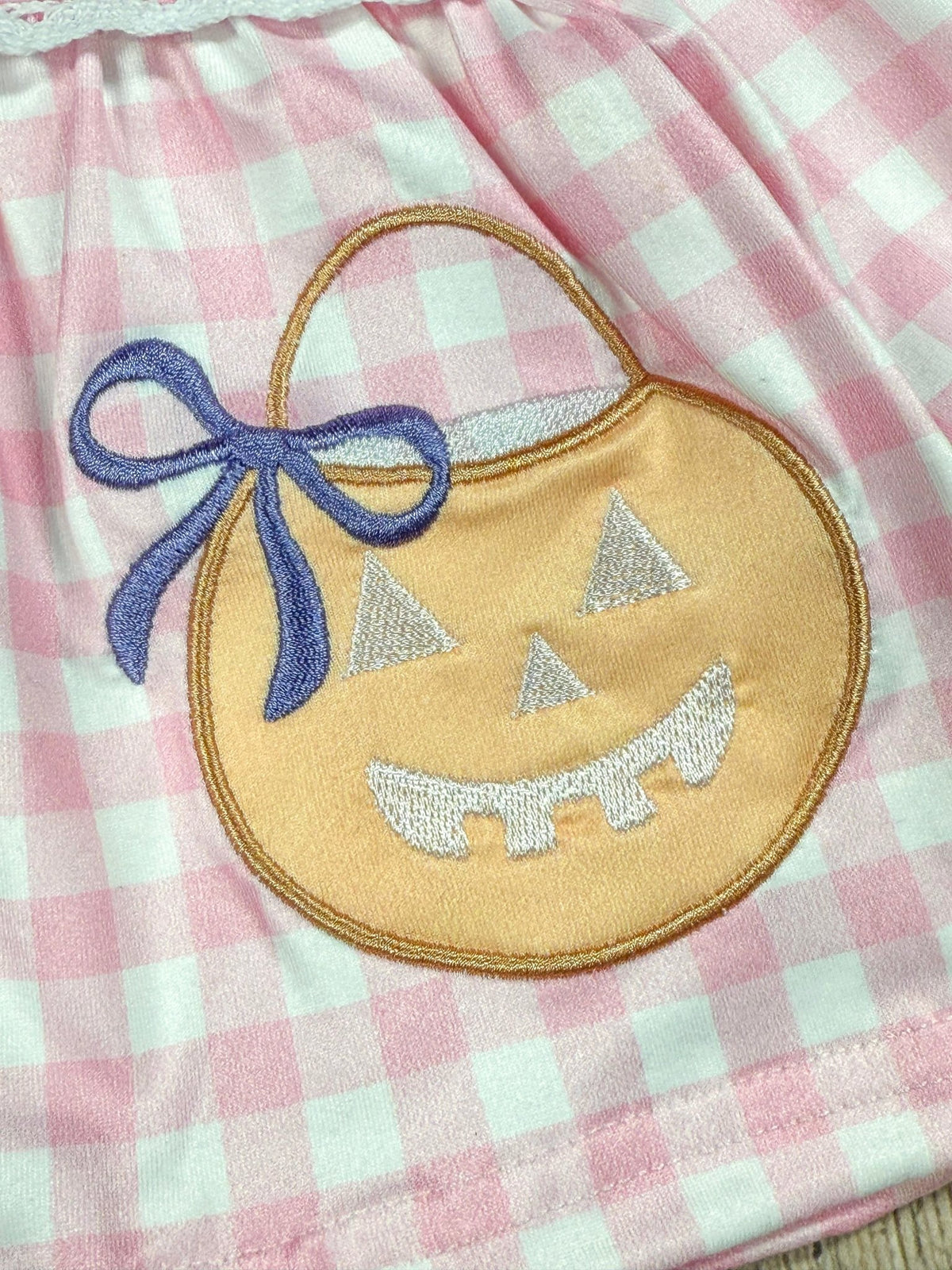 Embroidered pumpkin with a purple bow on pink gingham