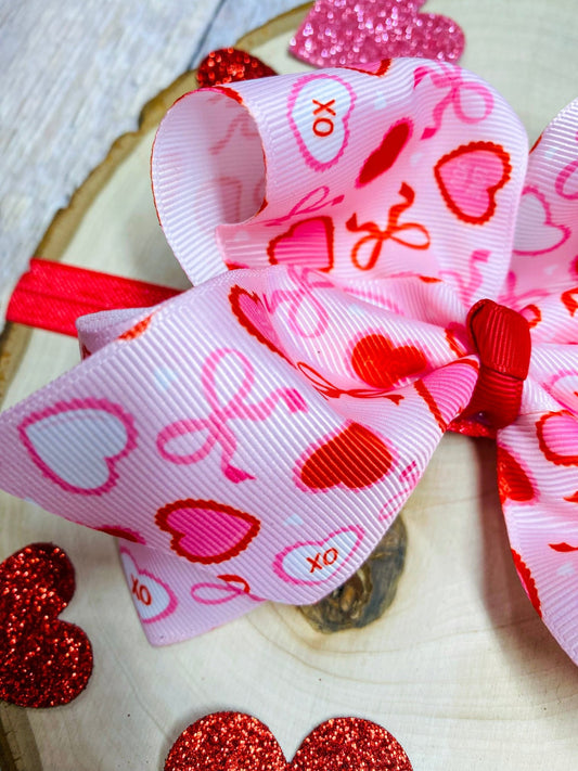 Heart-themed ribbon with red and pink designs on a wooden surface - Alternative view