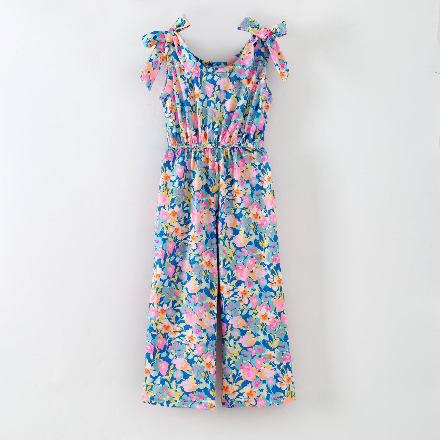 Colorful floral jumpsuit with bow straps on a white background