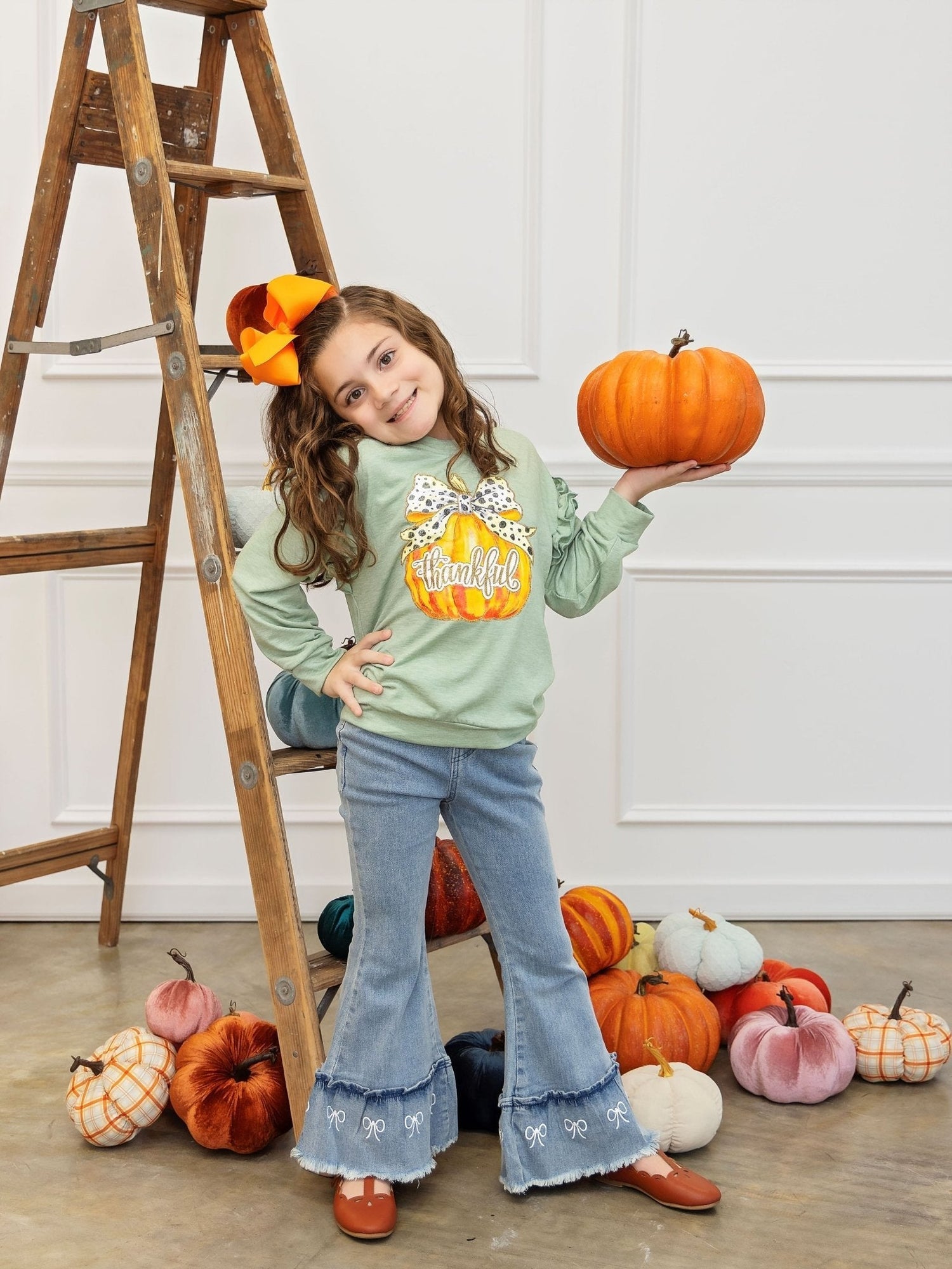 BOGO Turkey Tops. Code: TURKEYTOP child holding pumpkin in front of a ladder