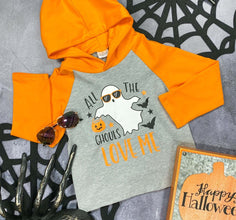 light grey with orange long sleeves and hood with text saying "all the ghouls love me" surrounding a ghost wearing sunglasses flay lay styled with decorative spider webs