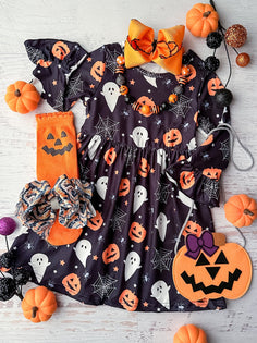 long sleeve dress with black background and ghosts pumpkins and spiderwebs all over dress. flat lay styled with decorative socks, bows, and various pumpkins