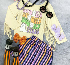 Halloween-themed toddler outfit with a "Spooky Vibes" fringe top, striped purple-orange skirt, ghost tights, sequin bow, pink and lavender bows, beaded necklaces, and black flower sunglasses arranged flat on a gray background.