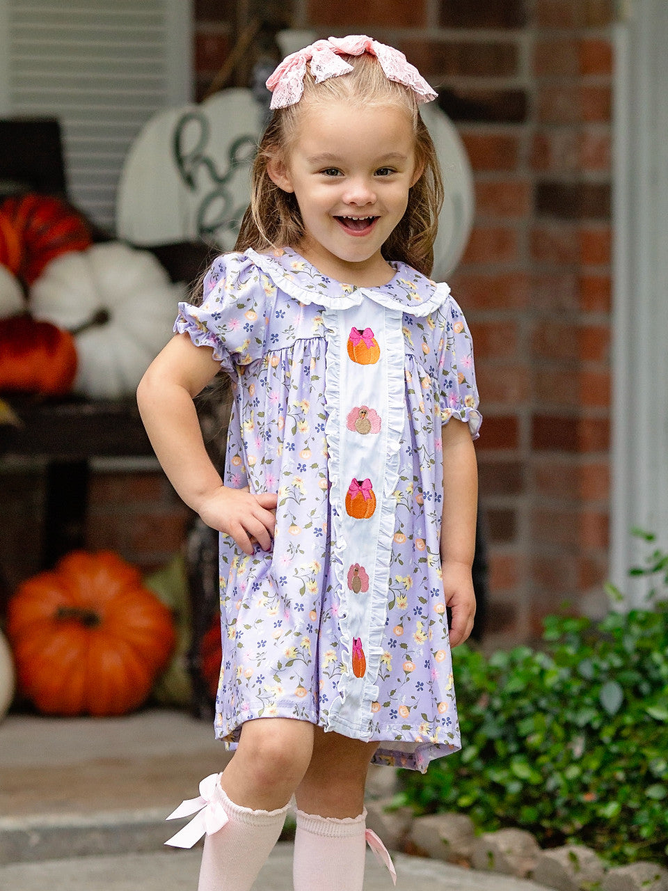 Turkey & Pumpkin Embroidered Floral Dress on a little girl standing on a fall front porch.