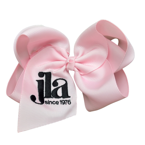 Pink hair bow with 'jla since 1976' text on a white background