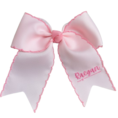 Pink and white hair bow with 'Ragan' embroidered on a white background