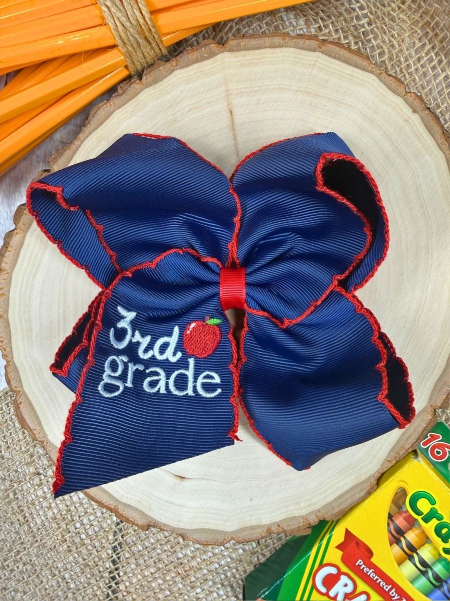 Blue and red bow with '3rd grade' text on a wooden surface