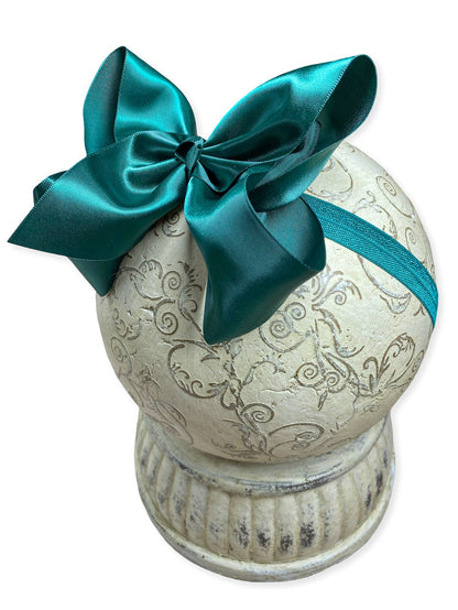 Decorative urn with a hunter green bow on a white background