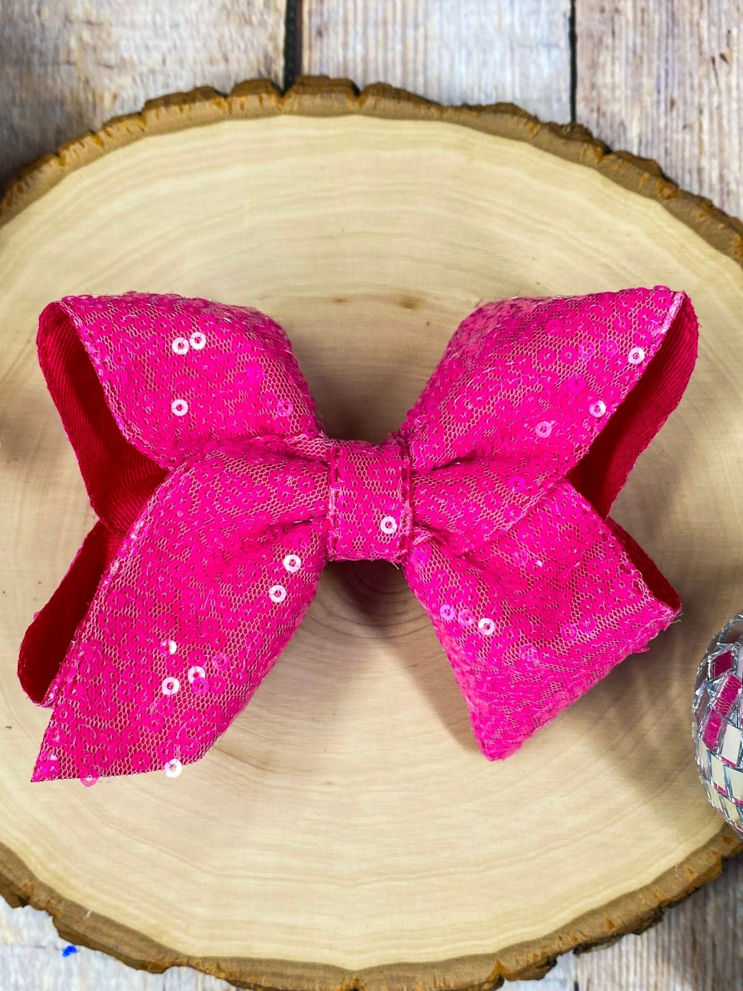 Hot pink sequin bow on a wooden surface