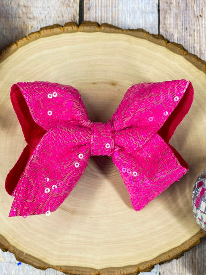 Hot pink sequin bow on a wooden surface