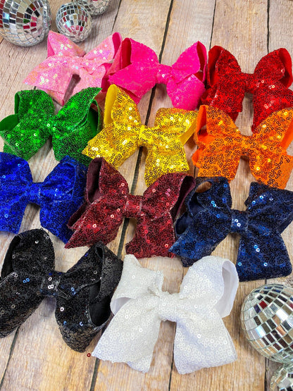 Colorful glittery bows on a wooden surface with disco balls around.