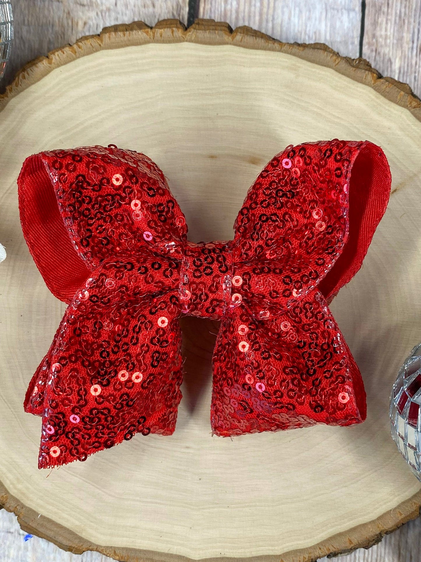 Red sequin bow on a wooden surface