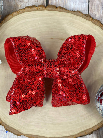 Red sequin bow on a wooden surface