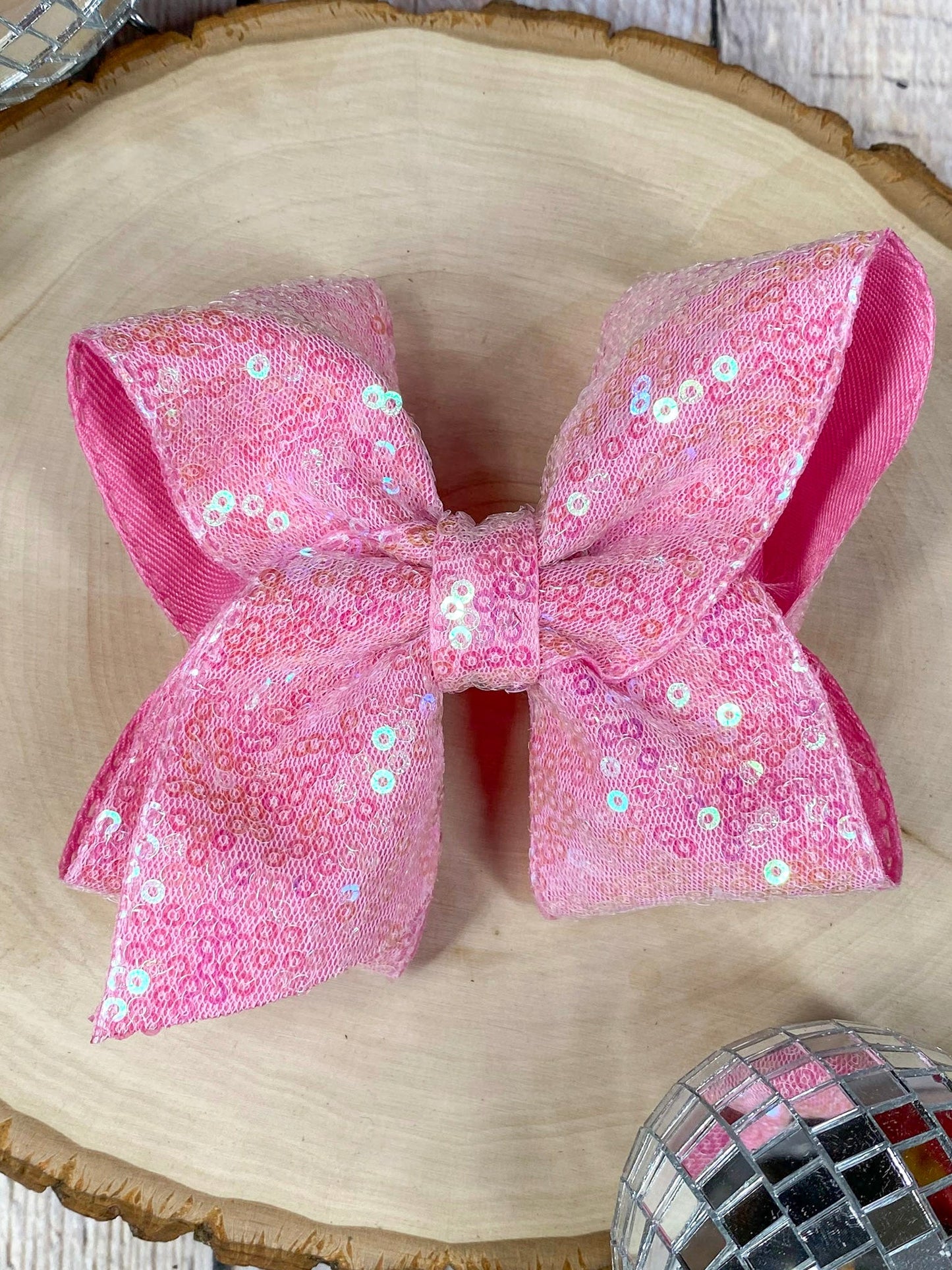 Pink sequined bow on a wooden surface