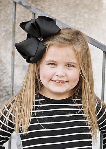Girl wearing a black 5.5 inch oversize rhinestone center knot hair bow