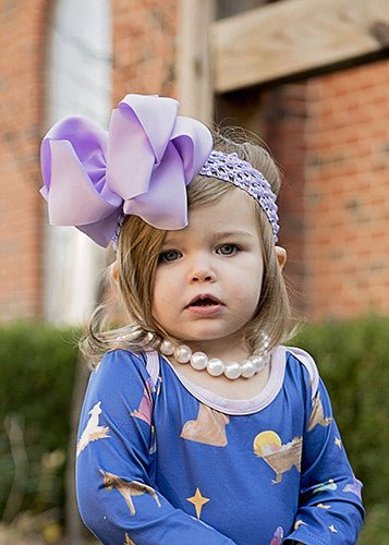 Girl wearing a lavender 5.5 inch oversize rhinestone center knot hair bow