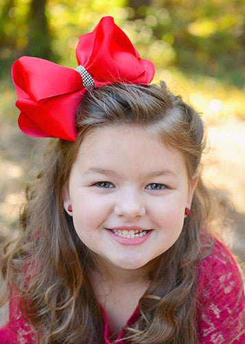 Girl wearing a 5.5 inch oversize rhinestone center knot hair bow